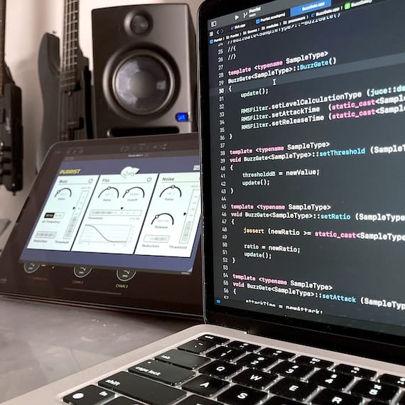 Zdjęcie przedstawiające laptop z widocznym kodem programu C++, w tle studio muzyczne
